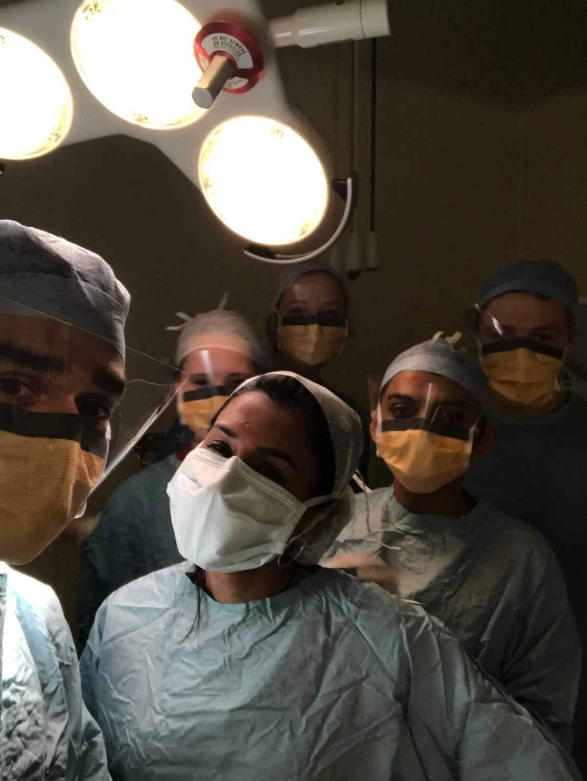 Kishan Rees with the surgical team in scrubs, caps and masks under the operating theatre lights.